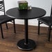 A black table with a round cherry and black table top and a black cast iron base plate.