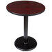 A Lancaster Table & Seating round table with a reversible black and cherry top and black metal base plate.