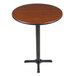 A Lancaster Table & Seating bar height table with a round walnut table top and cast iron base.
