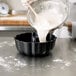 A person pouring flour into a Chicago Metallic fluted cake pan.
