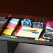 A Hirsh Industries right corner desk with a drawer full of office supplies.