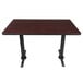 A Lancaster Table & Seating rectangular table with a reversible cherry/black top and black table base plates.