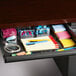 A drawer with a lot of stationery including sticky notes and pens.