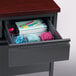 A black pedestal desk with a drawer full of stationery including a file cabinet and pen holder.