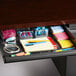 A black desk drawer filled with stationery and sticky notes.