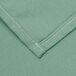 A close up of a seafoam green cloth with white stitching.
