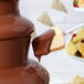 A chocolate fountain with a spoon dipping into milk chocolate.
