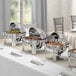 A buffet table with an Acopa Supreme round chafer and silverware on it.