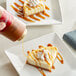 A hand pours Torani Puremade Pumpkin Pie Flavoring Sauce over a slice of cheesecake.
