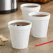 Three Dart white styrofoam cups filled with brown liquid on a counter.