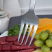 An American Metalcraft stainless steel cold meat fork holding cheese and grapes.
