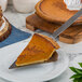 A slice of pumpkin pie served with an American Metalcraft stainless steel pie server.