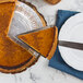 A slice of pumpkin pie being served with an American Metalcraft wavy stainless steel pie server.