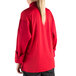 A woman wearing a Mercer Culinary red long sleeve cook jacket with a full mesh back.