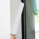 A hand using a white Unger ProFlex duster handle with a white Unger microfiber sleeve.