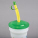 A 16 oz. clear plastic souvenir cup with a green lid and straw.