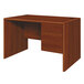 A wooden HON 10700 Series single pedestal desk with two drawers in cognac wood finish.