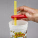 A hand holding a straw in a "Fun at the Fair" souvenir cup with a red lid.