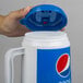 A person holding a 32 oz. Pepsi Mini Tanker with a blue lid.