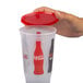 A hand holding a 32 oz Coca-Cola plastic cup with a red lid.