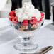 A Libbey dessert glass filled with a dessert topped with berries and whipped cream.