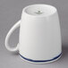 A white porcelain tall cup with a blue handle and blue trim.