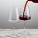 A close-up of red wine being poured into a Stolzle red wine glass.