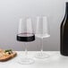 A pair of Stolzle red wine glasses on a marble table next to a bottle of wine.