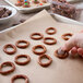 A person putting chocolate on Wege of Hanover pretzels on a tray.