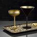Two Stolzle matte black and gold martini glasses on a tray.