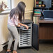 A girl opening a Kensington Black Security Chromebook / Tablet Charging Cabinet to access a laptop.
