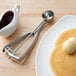 A plate of pancakes with a scoop of butter on top and a Vollrath stainless steel ice cream scoop.