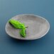 An Elite Global Solutions Santiago silverstone melamine plate with a mint leaf on it.
