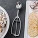 A metal Vollrath oval ice cream scoop with a bowl of food and a spoon.