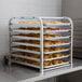 A Regency unassembled countertop sheet pan rack holding trays of croissants.