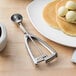 A white plate with a stack of pancakes topped with ice cream, butter, and syrup next to a Vollrath stainless steel ice cream scoop.