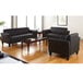 A black Alera Reception Lounge Series leather sofa with wooden feet in a living room with black couches and a coffee table.
