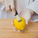 A person in white gloves cutting a lemon with Mercer Culinary garnish tools.