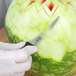 A person using Mercer Culinary Thai fruit carving knives to carve a watermelon.