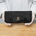 A person holding a black case with a logo for a Mercer Culinary Garde Manger knife set.