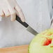 A person using a Mercer Culinary Garde Manger knife to cut a watermelon.