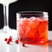 An Acopa hobnail rocks glass with a red cocktail and pomegranate on the rim.