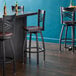 A Lancaster Table & Seating black swivel bar stool with a mahogany wood seat and back.