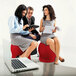 A group of people sitting on Safco Zenergy red ball chairs, one with a laptop and one with a piece of paper.