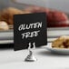 A gluten free sign on a stainless steel clamp-style table card holder.