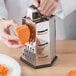 A person using a Choice stainless steel box grater to grate a piece of food.