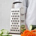 A Choice stainless steel box grater next to vegetables.