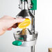 A person's hand squeezing a slice of lemon into a juicer cone.