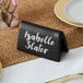 An Acopa matte black ceramic double sided table tent with the name "Isabelle Slater" on it.
