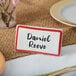 A white ceramic table tent sign with red border displaying the name Daniel Revere.